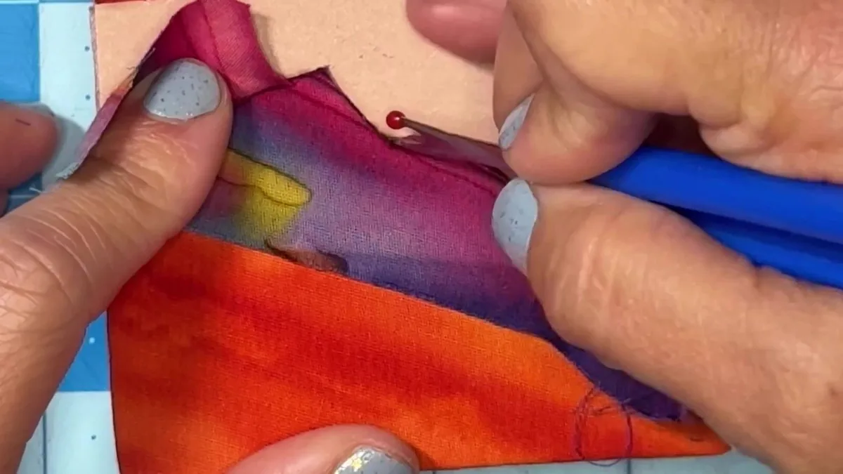 Module 2: close-up of tucking fabric into the practice board with a seam ripper